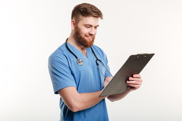 Portrait of a young male doctor writing on clipboard