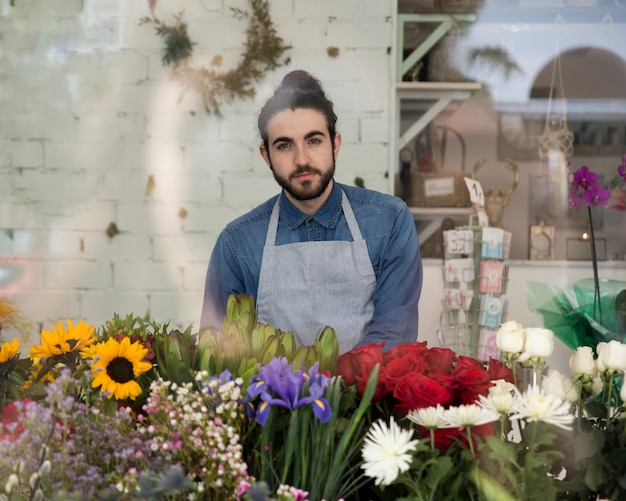 Portrait of a young male florist in apron with beautiful flowers