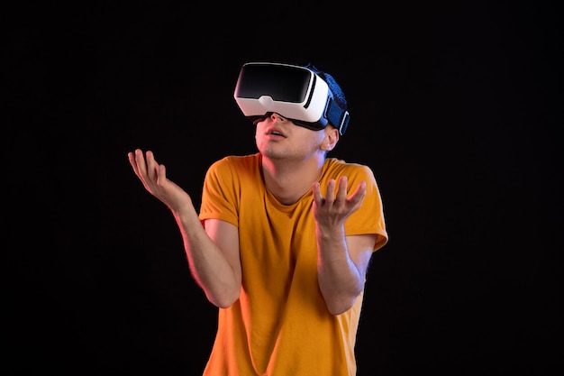 Portrait of young male playing virtual reality on dark wall