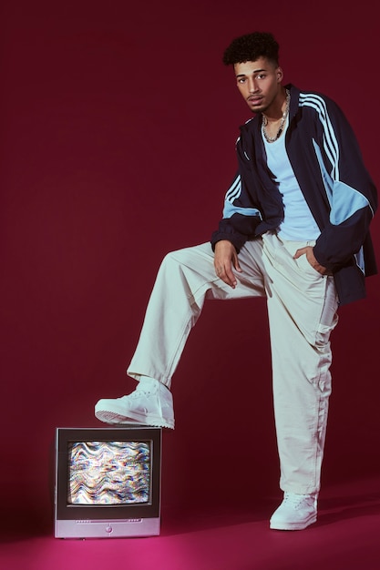 Portrait of young man in 2000s fashion style posing with tv