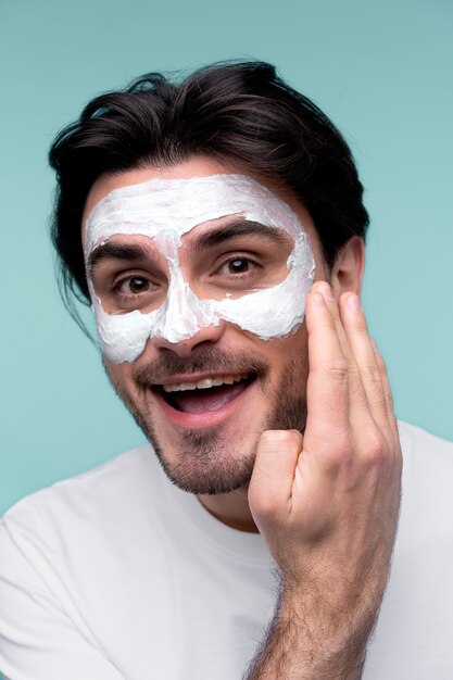 Portrait of a young man applying face mask