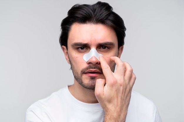 Portrait of a young man applying a nose patch Free Photo