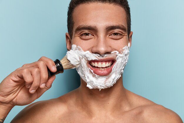 Портрет молодого человека, применяющего крем для бритья