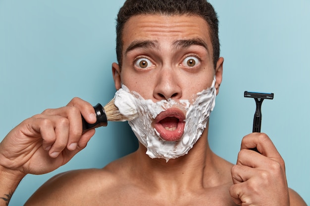 Портрет молодого человека, применяющего крем для бритья