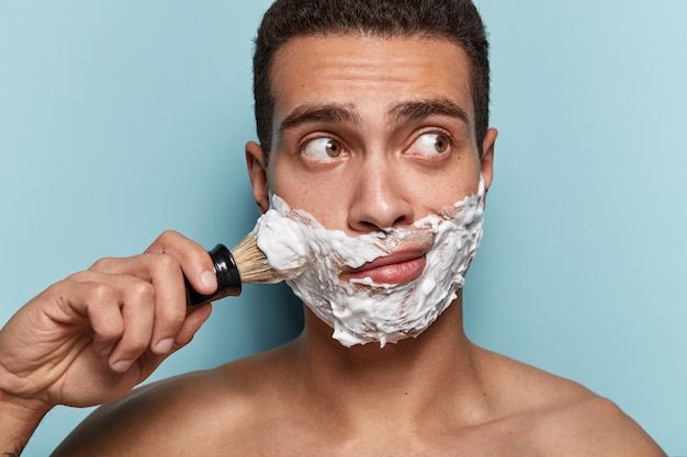 Portrait of young man applying shaving foam