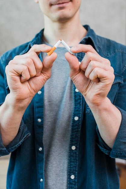 Free photo portrait of young man breaking cigarette