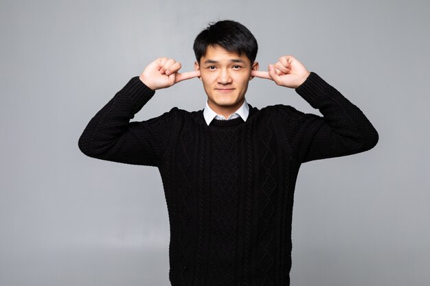 Portrait young man covering his ears, looking up, to say, stop making loud noise it's giving headache, isolated white wall. Negative emotions, face expressions