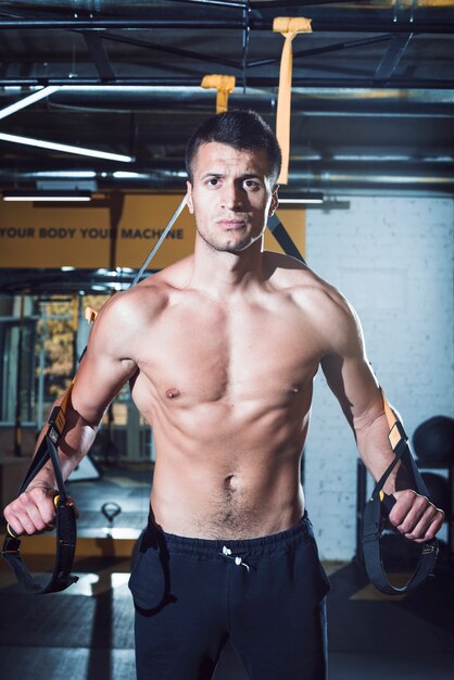 Portrait of a young man exercising with fitness strap