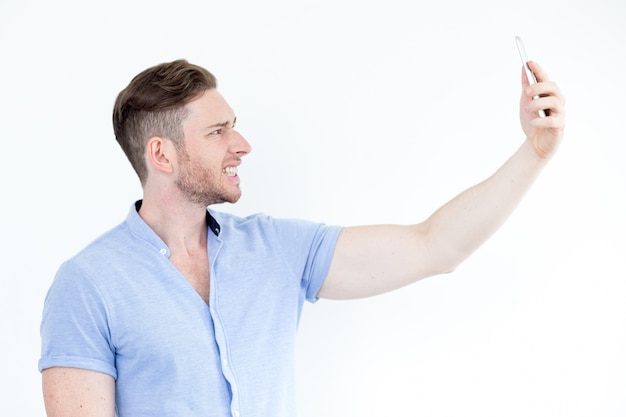 Портрет молодой человек grimacing и принимая selfie