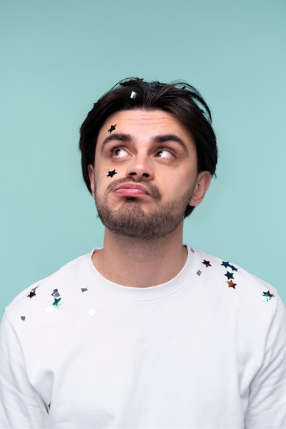 Free photo portrait of a young man having confetti on his head and shoulders