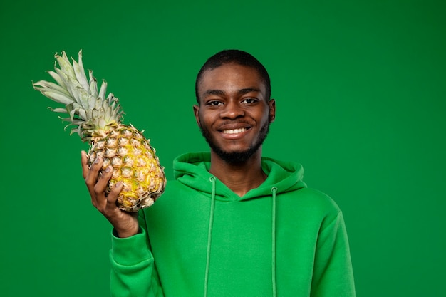 Free photo portrait of young man holding pineapple