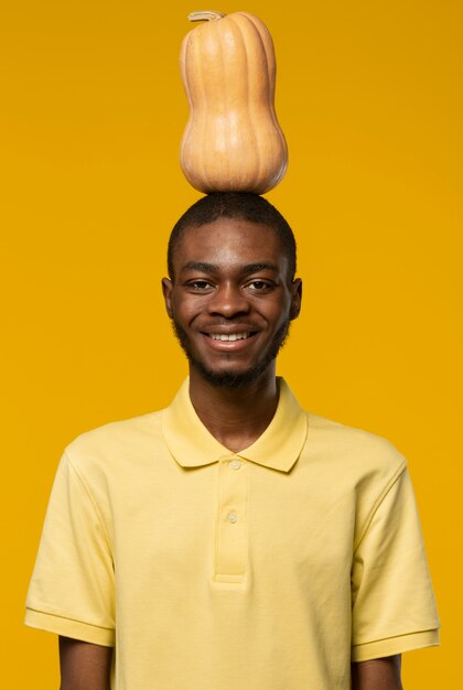 Portrait of young man holding pumpkin on his head