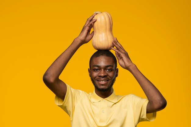 Portrait of young man holding pumpkin on his head