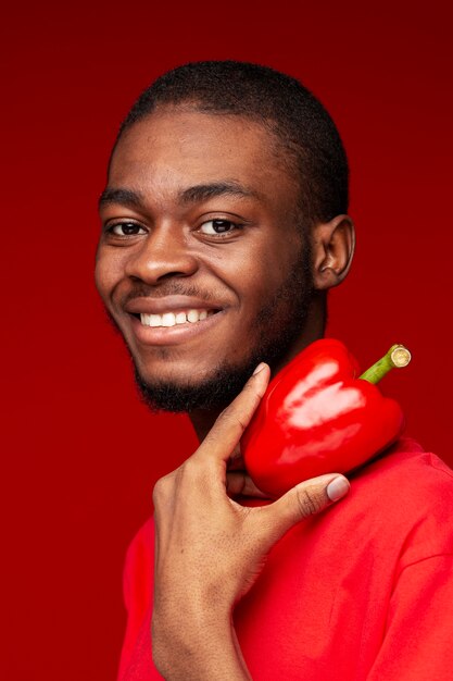 Portrait of young man holding red bell pepper