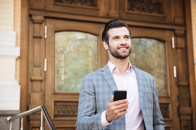 Portrait of a young man in jacket using mobile phone