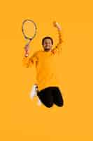 Free photo portrait young man jumping with tennis racket