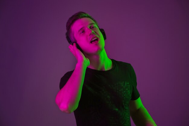 Portrait of young man listening to music with neon lights