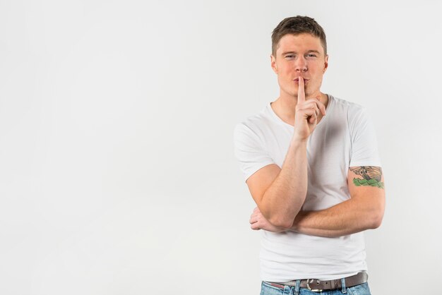 Portrait of a young man making gesturing for silence with finger