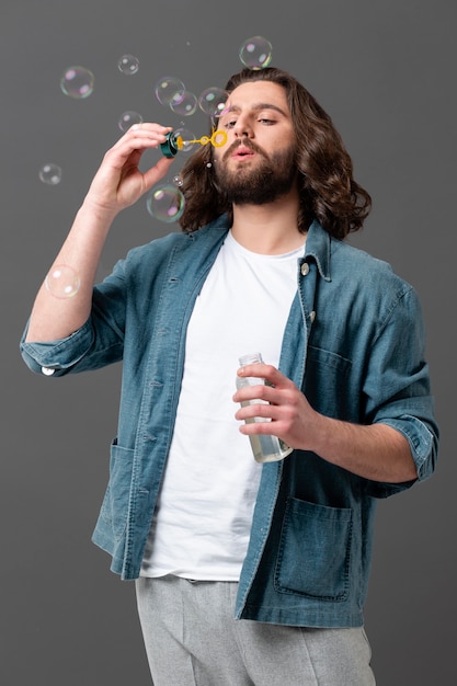 Free photo portrait young man making soap bubble