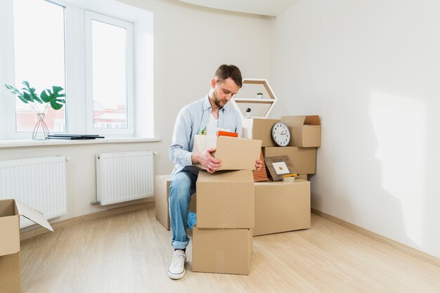 Portrait of a young man packing the cardboard boxes at home