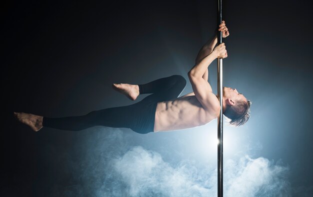 Portrait of young man performing a pole dance