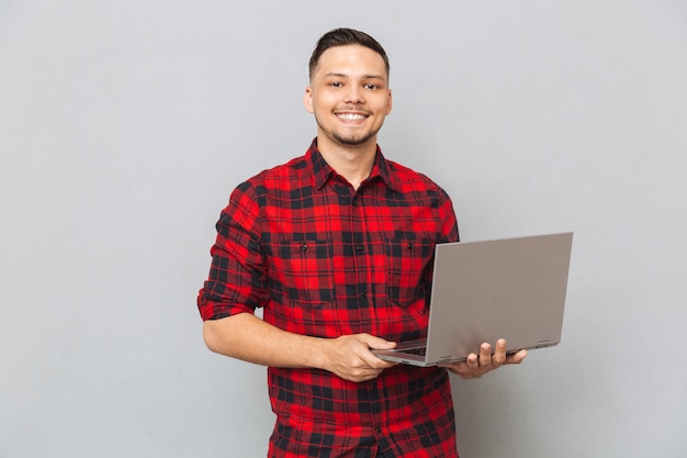 Portrait of a young man in plaid shirt holding laptop
