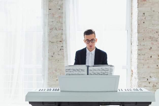 Portrait of a young man playing the piano sitting in front of window