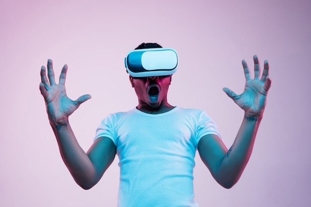 Portrait of young man playing in VR-glasses in neon light