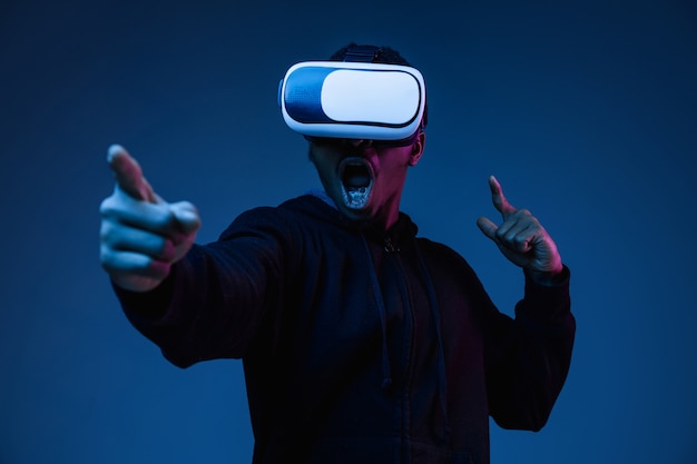 Portrait of young man playing in VR-glasses in neon light