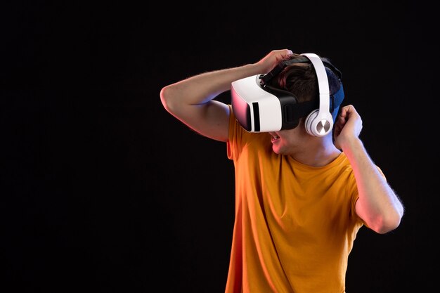 Portrait of young man playing vr in headphones on a dark wall