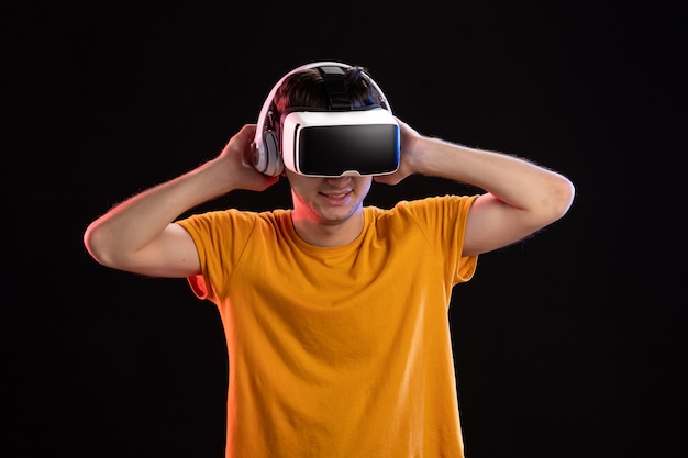 Portrait of young man playing vr in headphones on dark wall