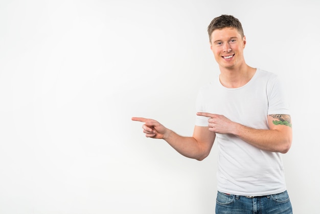 Portrait of a young man pointing finger looking to camera isolated over white background