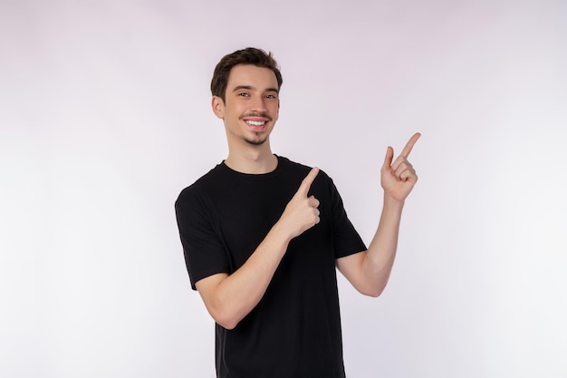 Portrait of young man pointing fingers at copy space isolated on white studio background