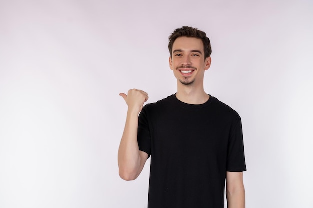 Portrait of young man pointing fingers at copy space isolated on white studio background