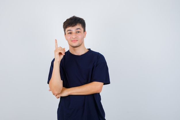 Portrait of young man pointing up in black t-shirt and looking confident front view