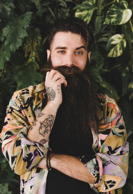 Free photo portrait of a young man raising his eye pulling his mustache