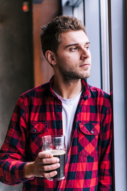 Portrait of a young man in red checkered pattern shirt holding the beer glass