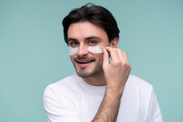 Portrait of a young man removing the under-eye patches from his face