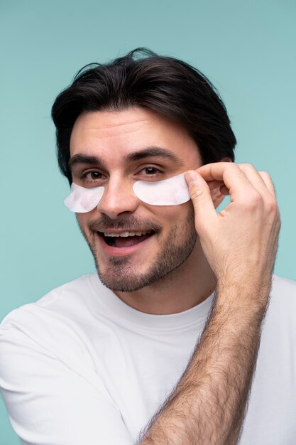 Portrait of a young man removing the under-eye patches from his face