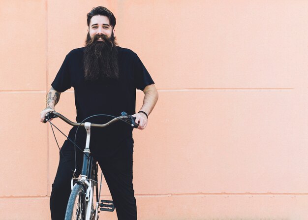 Portrait of a young man riding on the bicycle against beige background