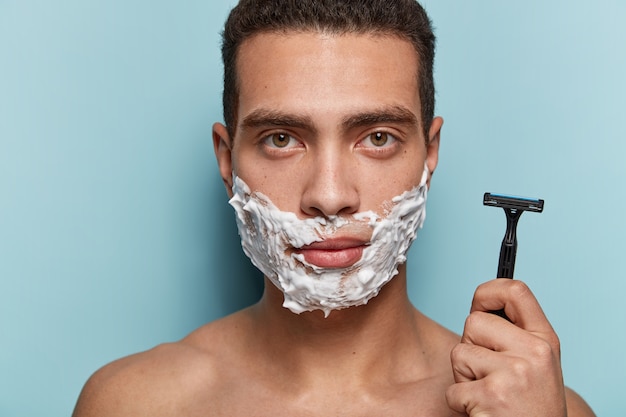 Free photo portrait of young man shaving his beard