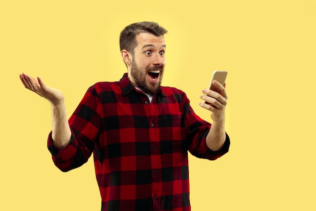 portrait of young man in shirt.Front view. Trendy colors. Getting crazy of news in smartphone.