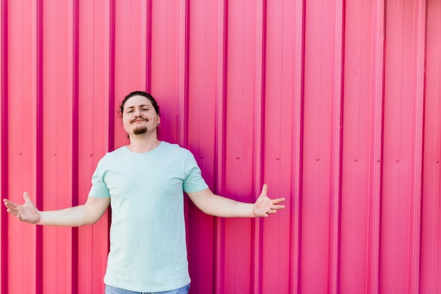 Free photo portrait of a young man shrugging against corrugated metal sheet