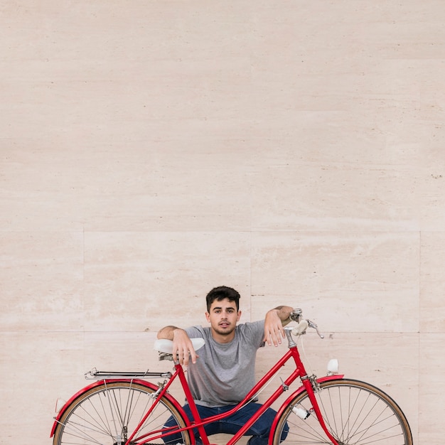 Portrait of a young man sitting behind bicycle