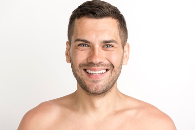 Portrait of young man smiling and looking at camera standing against white background