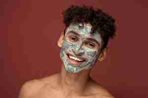 Free photo portrait of a young man smiling with a beauty face mask on