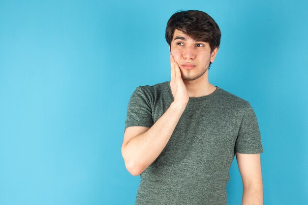 Portrait of a young man standing against blue.