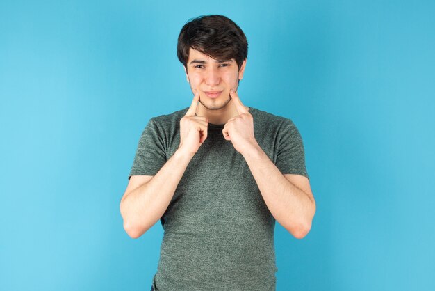 Portrait of a young man standing against blue.