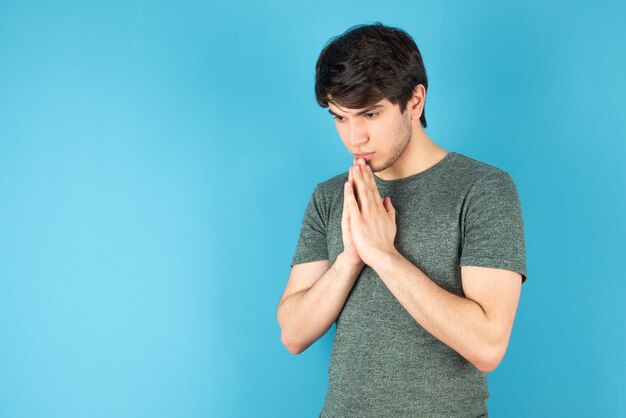 Portrait of a young man standing against blue.