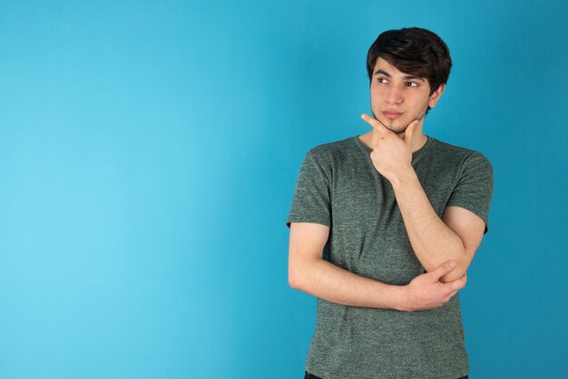 Portrait of a young man standing against blue.